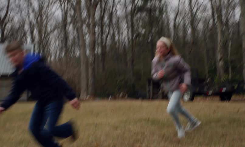 Two children in an outdoor backyard playing tag