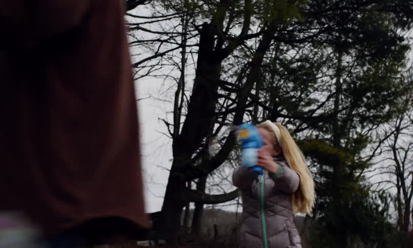 Little girl throwing soap bubbles at another boy and an old man outdoors