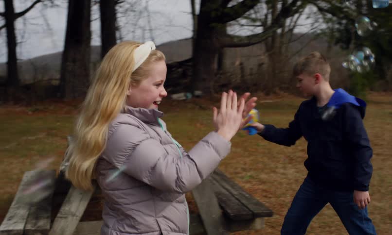 Grandfather playing with his  two grandchildren with soap bubble guns outdoors