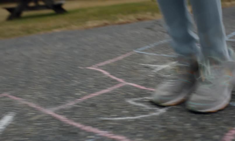 Legs of a child playing hopscotch in a backyard