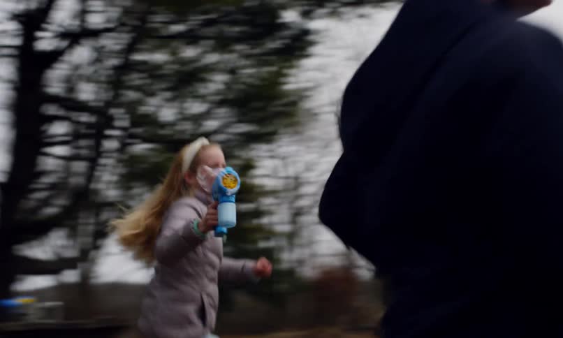Blonde girl runs holding a soap bubble gun