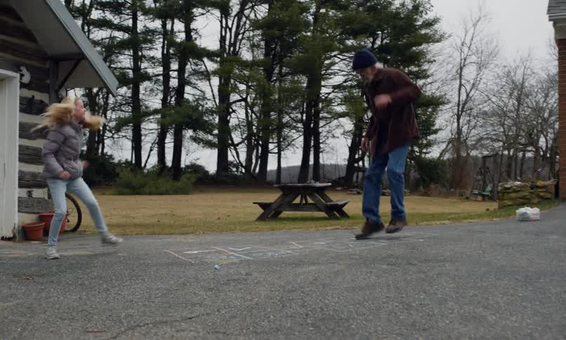 Granddaughter and her grandfather playing hopscotch in a backyard
