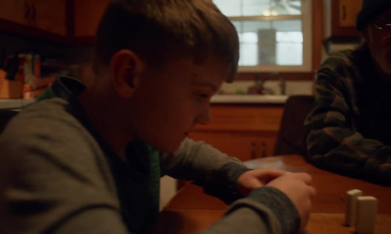 Grandfather and his grandchildren play with dominoes while sitting at the kitchen table