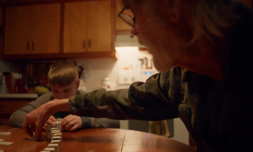 Grandfather sitting at the table with his two grandchildren playing dominoes