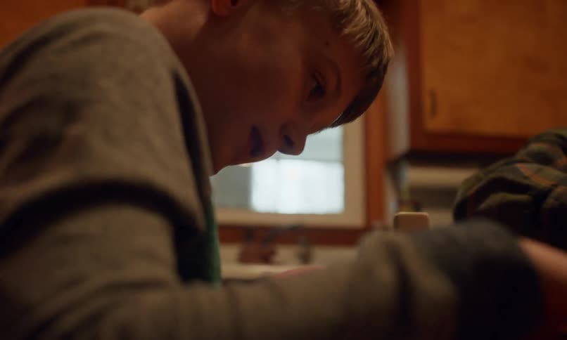 Boy sitting at table with his grandfather building stacks of dominoes