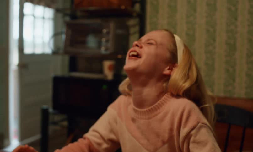 A girl laughs as she plays dominoes with others