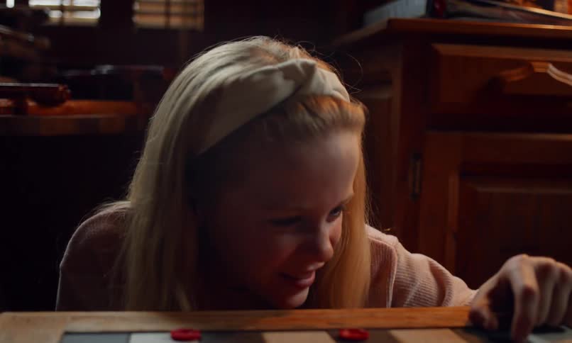 Portrait of a happy little girl while playing checkers with someone else