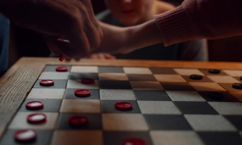 People play checkers moving the pieces on the wooden board