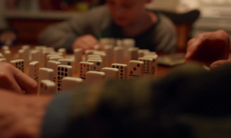 Hands carefully arrange dominoes in a complex pattern creating an intricate setup for a chain reaction