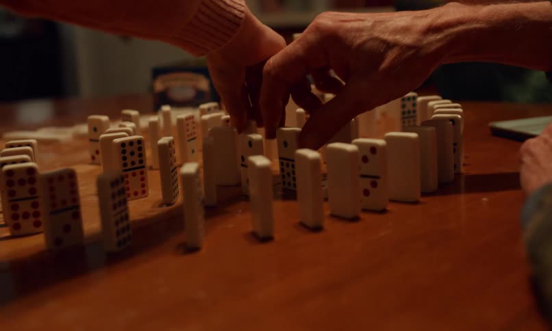 Grandfather sitting at a table playing dominoes with his two young grandchildren
