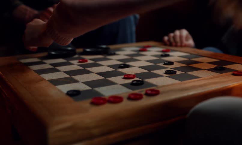 A man plays checkers on a game board with chldren in a room