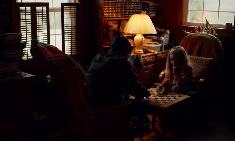 Adult person playing board game with two children in living room
