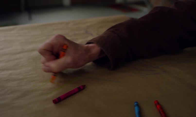 Elderly man drawing on a poster board with crayons along with a little blonde girl