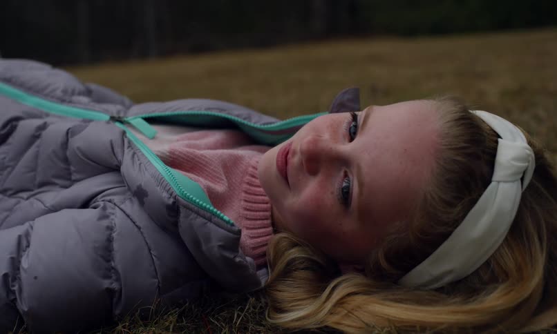 A young girl with a bright smile lies on the grass enjoying the moment