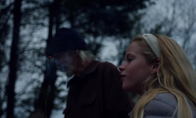 A man watches as a girl blows out a flame on a stick