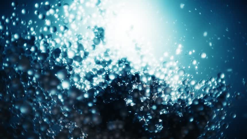 The effervescent bubbles illuminated by a bright light source dance in the deep blue liquid