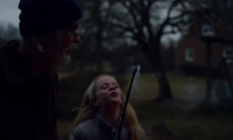 Grandfather putting out a fire on a branch next to a little girl