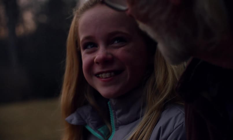 A girl and her father nod and smile at each other outside
