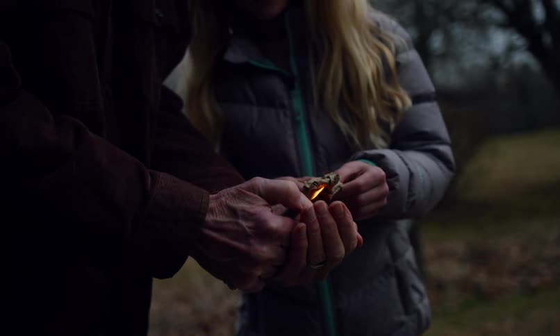 A man lights a paper and the girl throws it down