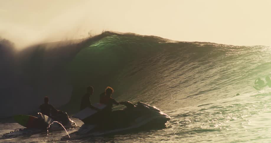 People on jet skis wait as a wave crashes in front of them