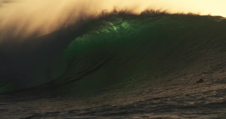 Men ride an aquatic vehicle near a swimmer while a large wave crests under a red tinted sky