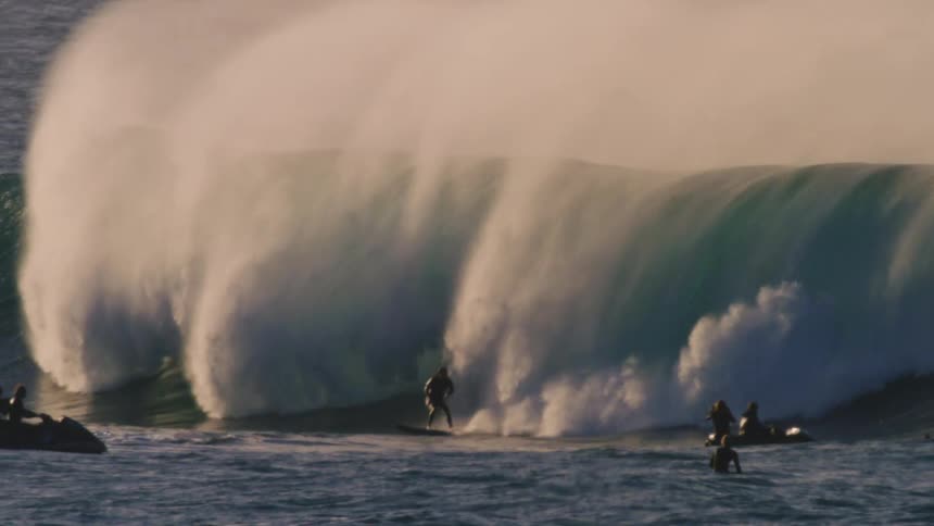Surfer riding a tubular wave with spectators on jetskis watching