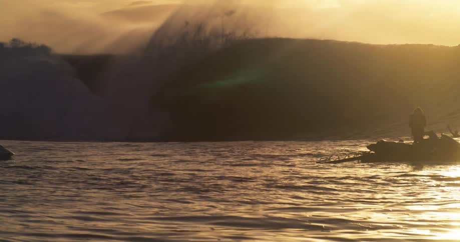 People on jet skis following surfers on large tubular waves in the ocean