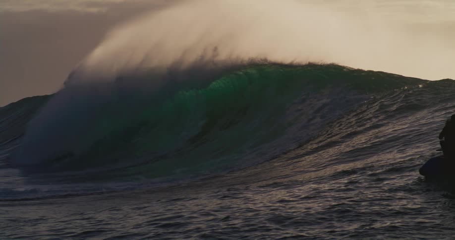 Big wave breaking in the ocean and silhouette of people watching