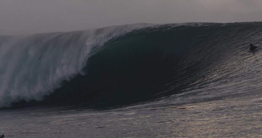 A photographer takes pictures as people ride a large wave