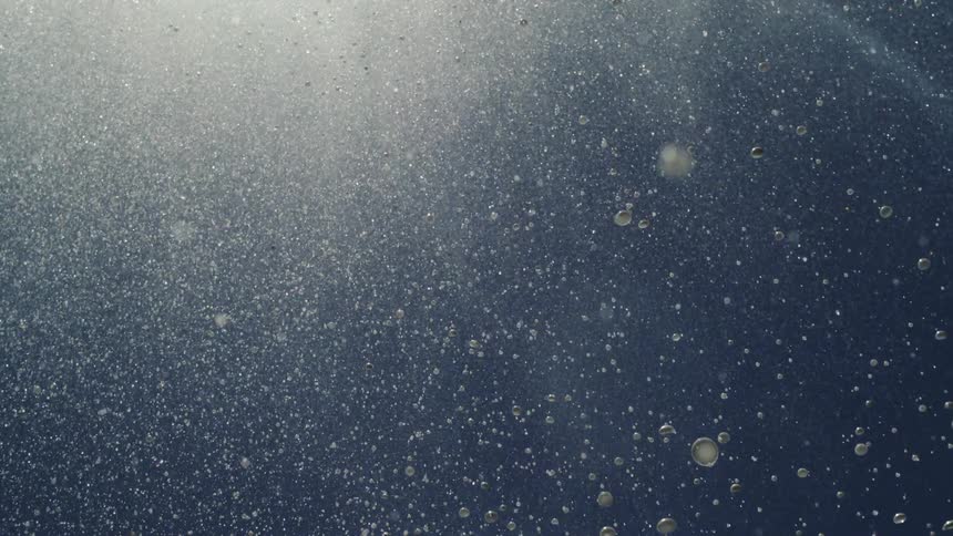 Water droplets fall through the air as a coastal area comes into view