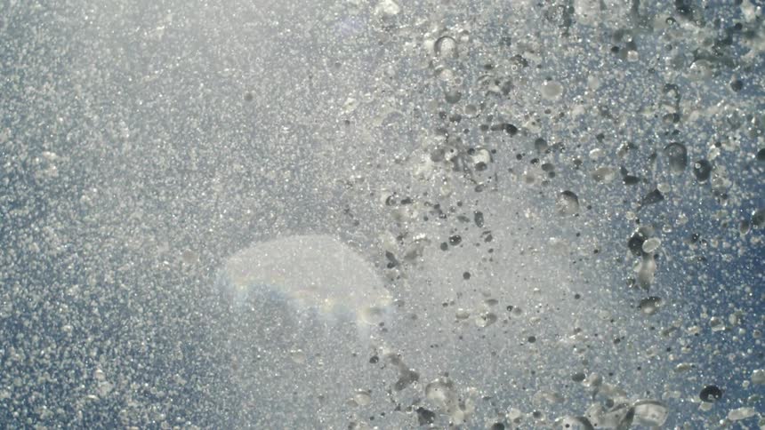 Closeup of a jet of water with foam against a blue sky