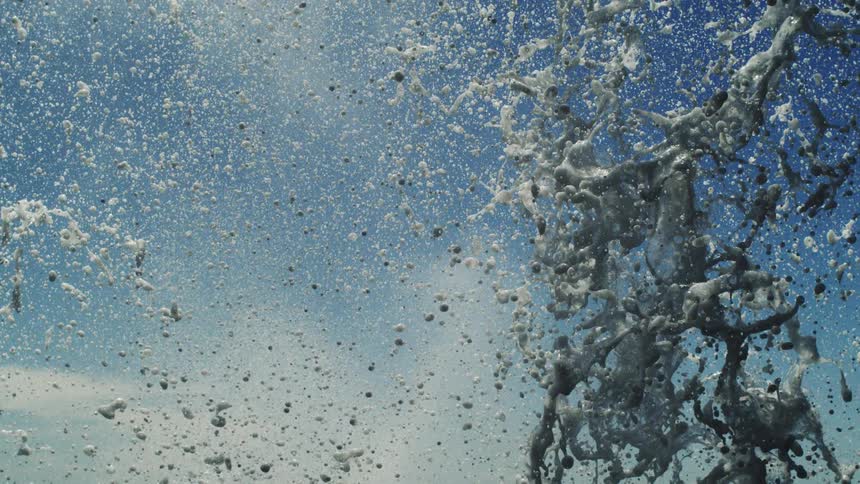 A large amount of water making a splash falling down on an exterior with blue sky