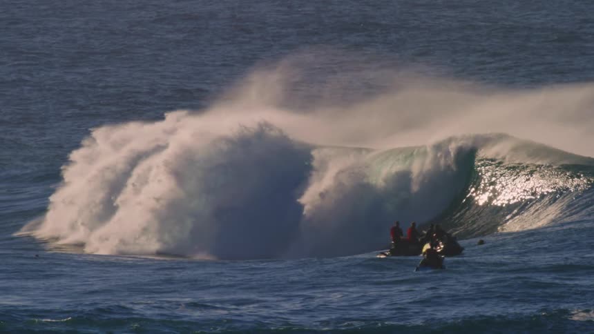 People on jet skis following surfers on waves