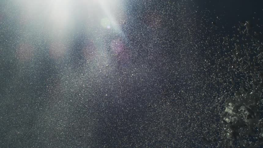 Foamy water rising and falling against a night sky