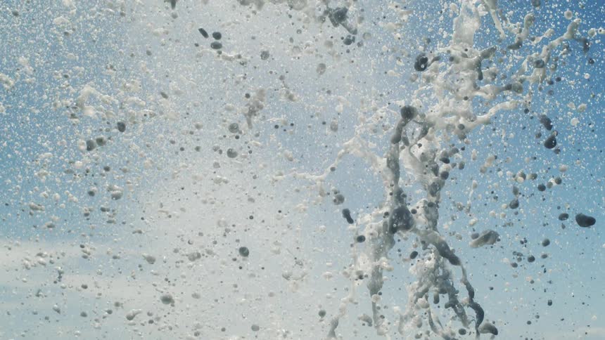 Splash of water with foam against a blue sky