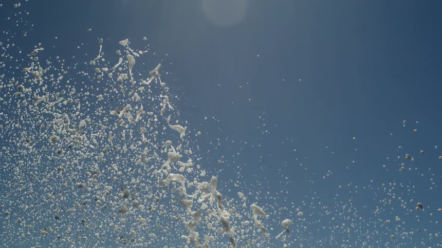 Water splash with foam from waves rising against a blue sky