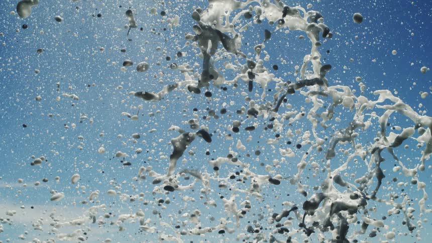 Jet of water ejected against the blue sky and the shining ocean in the background