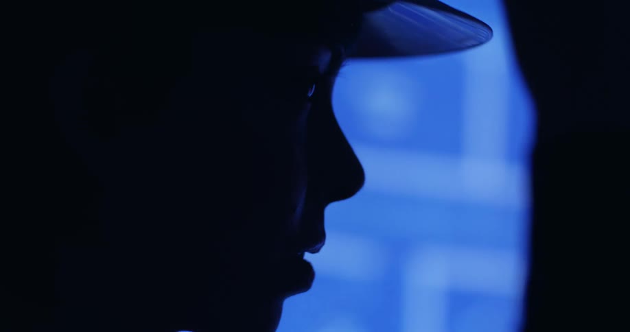 Side silhouette of a woman in a hard hat talking and standing in front of a digital blueprint projector.