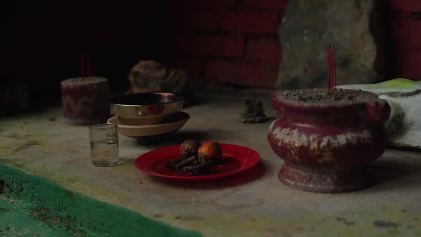 Ritual offering with food incense and containers is arranged on a surface