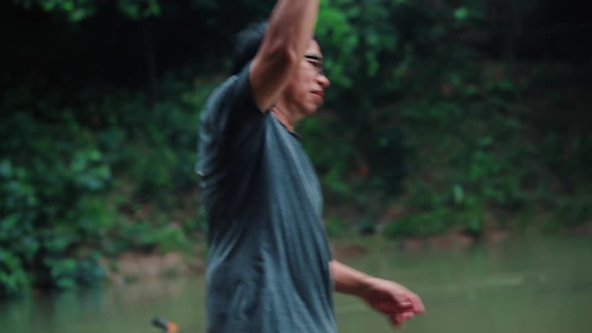 A man is using a net to fish in a pond