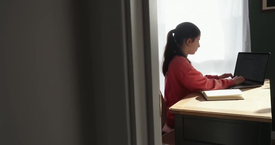 Woman in a room typing on laptop