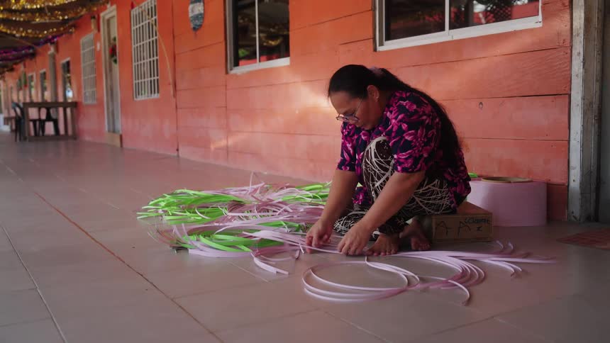 A woman prepares plant material to start weaving