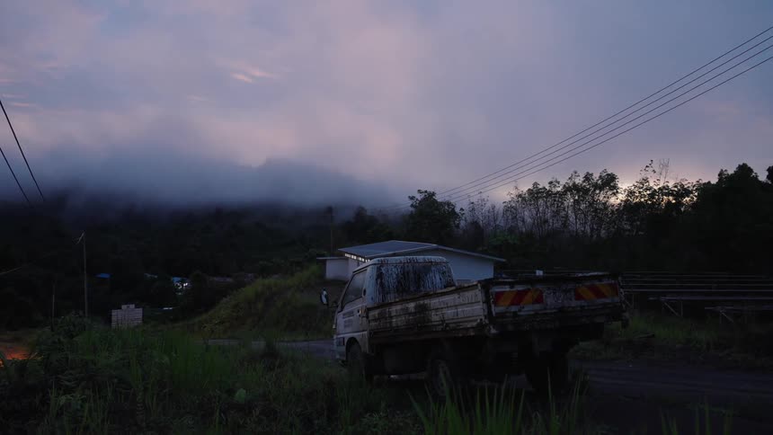 Small truck parked on the side of the road in a misty purple sky sunrise