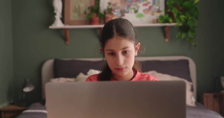 Teenage girl studying on her mac computer in her bedroom