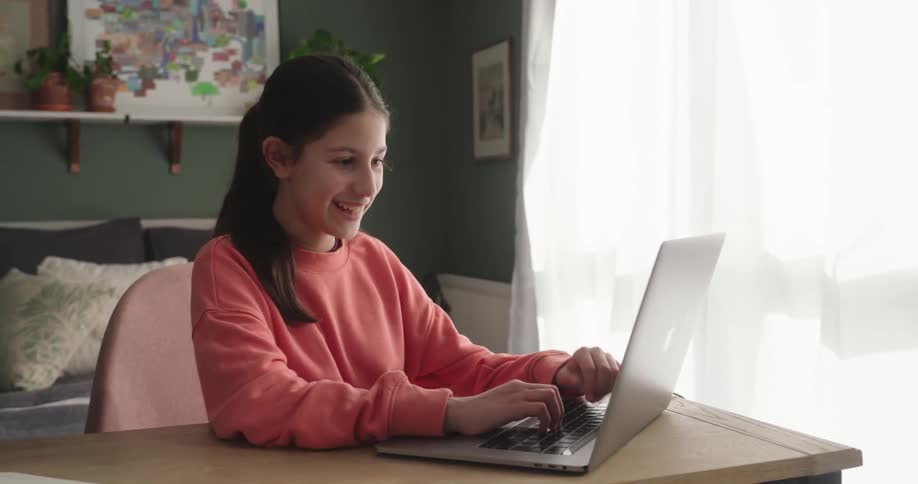 Girl sitting in a room typing on a laptop