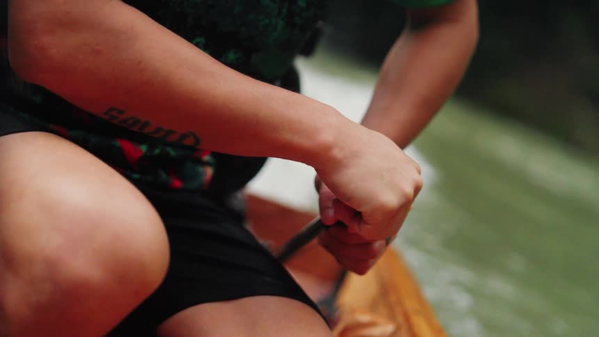 A person is steering a motorized boat on a river with the water visible in the background