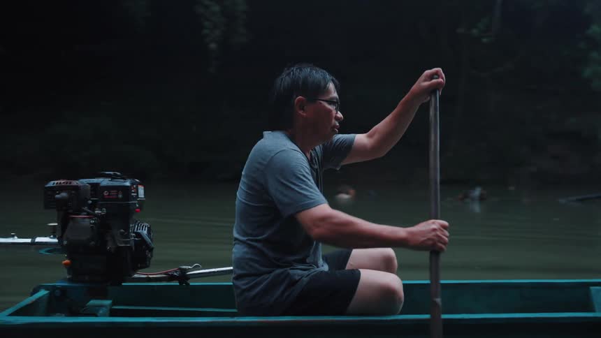 Man in a wooden boat rowing down the river