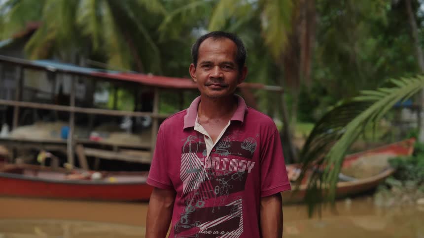 Man on the bank of a river with tropical palm trees in the background