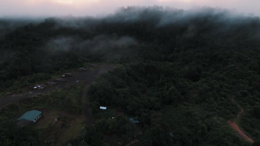 Closet scene of a community in the middle of mountains with forests and intense clouds