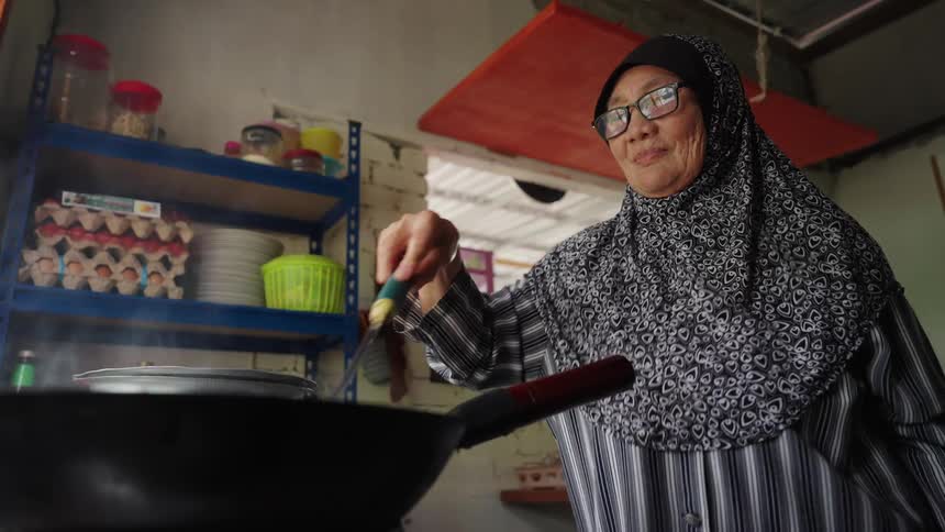 Woman with an apron on her head cooking in a pot